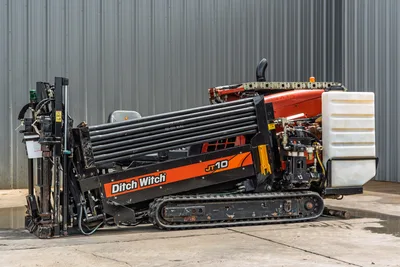 2018 Ditch Witch JT10 HDD drill, side view, drill pipe rack loaded, rubber tracks, fluid tank, hydraulic components visible