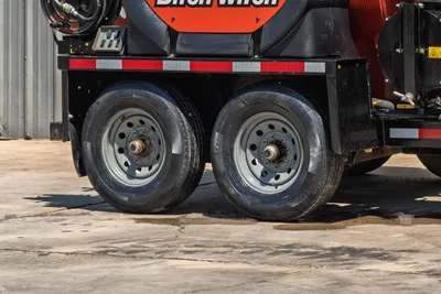 2023 Ditch Witch HX30 mud mixer trailer tandem axle close-up, steel wheels, red reflective tape, black tank visible above frame