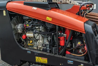 2016 Ditch Witch JT9 open engine compartment showing 66hp diesel engine, cooling fan, filters, hydraulic lines, and drill pipe rack