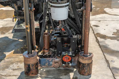 2023 Ditch Witch JT20 front anchor assembly, worn stabilizer feet, drill pipe guides, hydraulic components, and fluid bucket visible