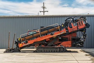 2014 Ditch Witch JT100 Mach 1 HDD rig, full profile view, drill pipe loaded on angled carriage, rubber tracks, hydraulic lines visible