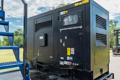 American Augers M300DH mud system generator enclosure, black steel housing with vents, inspection window, safety labels, wear visible