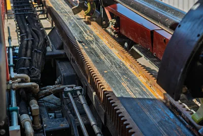 Close-up angle of Ditch Witch JT30 All Terrain carriage, rack and pinion drill rack, hydraulic hoses, and pipe rack frame.