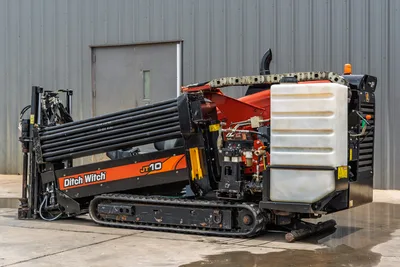 2018 Ditch Witch JT10 HDD drill, rear 3/4 view showing loaded drill pipe rack, fluid tank, hydraulics, rubber tracks