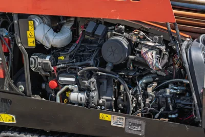 2022 Ditch Witch JT20 open engine compartment showing 74hp diesel engine, hydraulic pumps, wiring harness, and safety labels