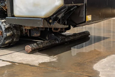 2018 Ditch Witch JT10 undercarriage close-up showing rubber track, used drill pipe with wear, fluid reservoir, and frame components