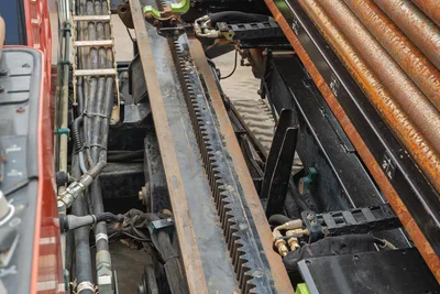 Ditch Witch JT25 rack and pinion drive system, drill pipe magazine, and hydraulic hoses of HDD drill unit.