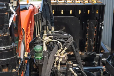2017 Ditch Witch JT30 hydraulic manifold, hose bundle, fittings, and green spin-on filter; close-up of mid-frame hydraulic system