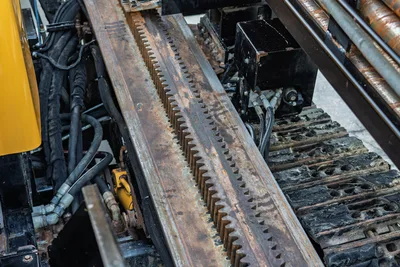 2019 Vermeer D40x55 S3 HDD drill rack and pinion carriage rail, close-up showing wear, hydraulic hoses, and rubber track