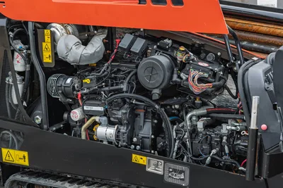 Ditch Witch JT20 engine compartment showing 74 hp power plant, hydraulic pump, electrical systems, and drill pipe rack detail