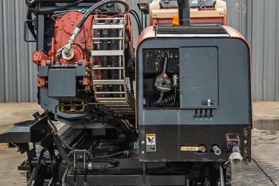 Ditch Witch JT3020 Mach 1 side view showing carriage, drill pipe rack, hydraulic hoses, and open remote control station panel.