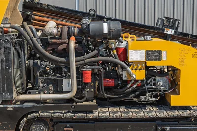 Open engine bay of 2009 Vermeer D36x50 Series II showing turbocharger, hydraulic lines, filters, and steel tracks.