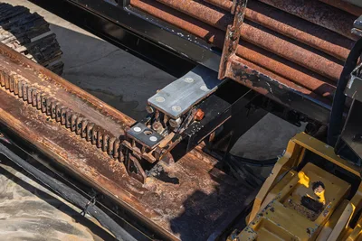 Vermeer D40x55 S3 drill frame close-up showing worn rack gear, carriage assembly, drill pipe rack with surface rust, yellow vise visible