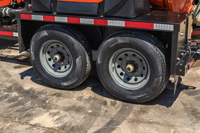 2023 Ditch Witch HX30 mud mixer trailer tandem axle closeup, dual tires with gray steel wheels, reflective red tape on frame