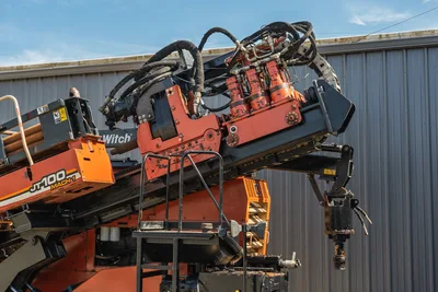 2014 Ditch Witch JT100 Mach 1 drill carriage and spindle assembly elevated on thrust frame, hydraulic hoses visible