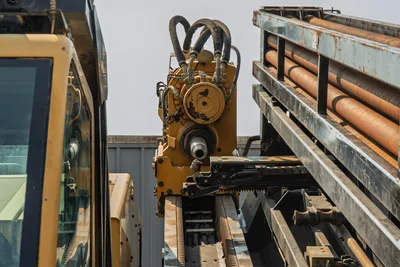 2017 Vermeer D100x140 S3 spindle and rotary head close-up, drill pipe rack visible with multiple 3.5" pipes loaded