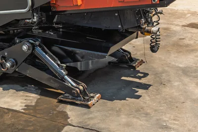2023 Ditch Witch JT20 hydraulic anchor/stabilizer legs extended, close-up undercarriage view, wear on foot pads visible