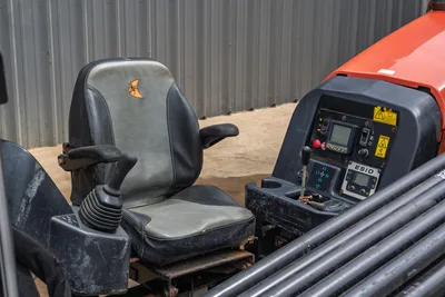 2018 Ditch Witch JT10 operator station, featuring worn seat, control joystick, ESID display, and drill pipe rack housing.