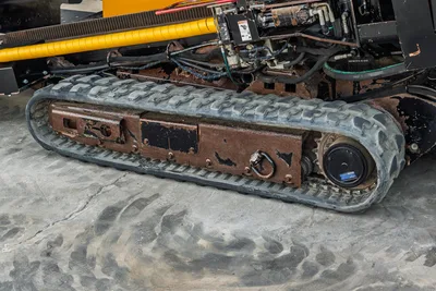 2016 Vermeer D23x30 S3 rubber track close-up showing worn undercarriage, drive sprocket, hydraulic lines, and yellow drill pipe above