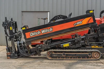 2021 Ditch Witch JT25 horizontal directional drill, side view, showing tracks, pipe rack, and drill carriage assembly.