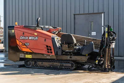 Ditch Witch JT10 HDD rig with tracked undercarriage, drill pipe bundle, operator cab, and right-angle drill head assembly, side view
