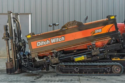 2021 Ditch Witch JT28 HDD drill, driver-side view, orange bodywork, carriage assembly, hydraulics, rubber tracks, drill rod visible