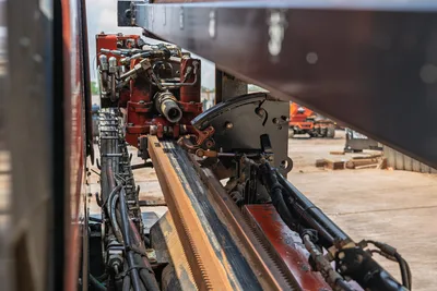 2017 Ditch Witch JT20 carriage assembly, rack-and-pinion thrust track, hydraulic rotary head, and hose bundle, close-up side view