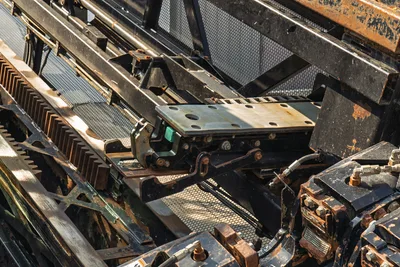 2017 Vermeer D100x140 S3 drill frame close-up showing carriage, rack-and-pinion thrust system, vise, and hydraulic lines with wear patina