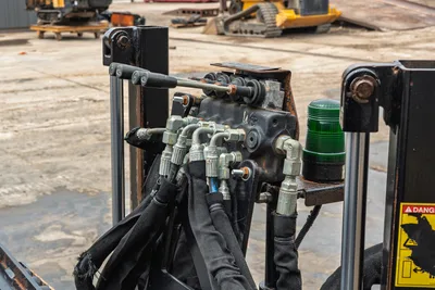 Ditch Witch JT10 hydraulic control bank with manual levers, diagnostic light, and sleeved hoses on the drill frame.