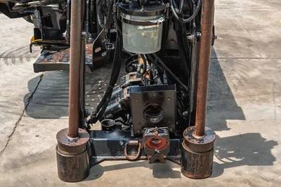 2017 Ditch Witch JT20 front anchor assembly, dual anchor rods with worn cylinders, vise block, hydraulic lines, close-up undercarriage view
