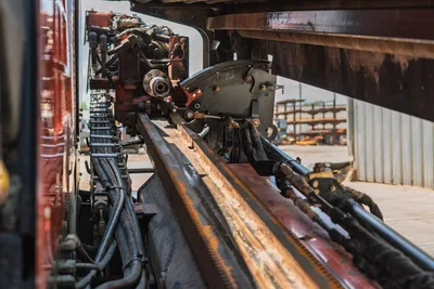 2021 Ditch Witch JT20 drill frame close-up showing rack-and-pinion thrust rail, carriage assembly, hydraulic hoses, and drive components