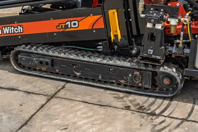 2018 Ditch Witch JT10 rubber track close-up showing drive sprocket, undercarriage wear, hydraulic components, and JT10 branding decal