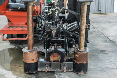 2021 Ditch Witch JT28 front anchor assembly, dual rust-worn anchor posts with hydraulic cylinders, vise block, and fluid lines visible