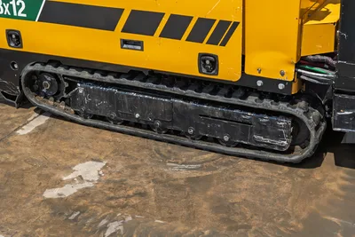 2021 Vermeer D8x12 HDD drill close-up of rubber track undercarriage, yellow machine body with black decals, visible hydraulic lines