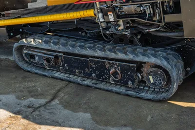 2016 Vermeer D23x30 S3 rubber track close-up showing drive sprocket, undercarriage, hydraulic lines, and yellow drill pipe