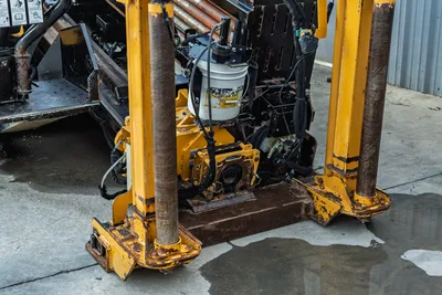 Vermeer D40x55 S3 front anchor/thrust frame close-up showing drill pipe, vise assembly, hydraulic lines, and anchor feet with wear visible