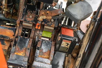 Overhead view of Ditch Witch JT3020 pipe vise and breakout system showing weathered steel jaws and safety warning labels.