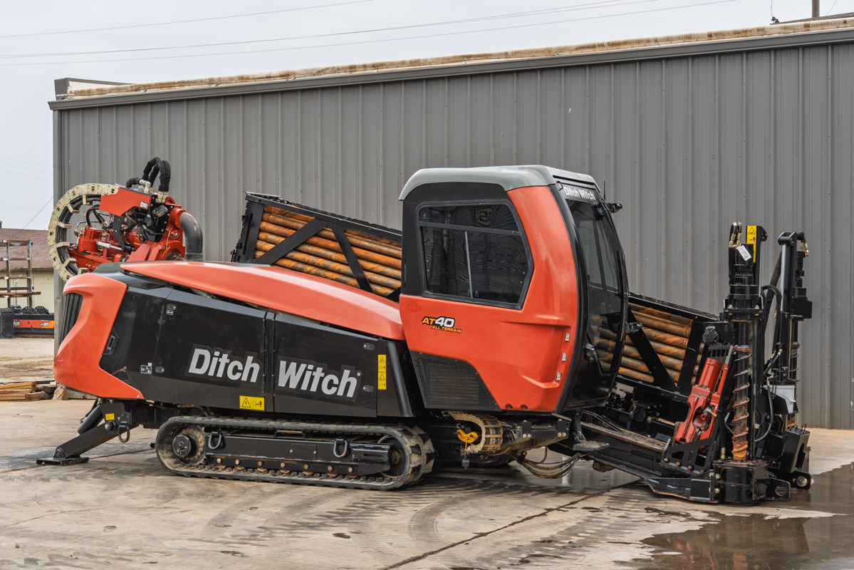 Side view of 2021 Ditch Witch AT40 All Terrain HDD with enclosed cab, drill pipe stack, tracks, and fluid management system.