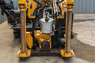 2018 Vermeer D24x40 S3 front anchor/thrust frame, vise assembly, hydraulic lines, and fluid bucket visible
