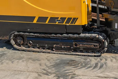 2021 Vermeer D40x55 S3 HDD drill close-up of steel undercarriage track, worn with mud and debris, drill pipe rack visible