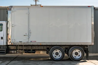 Side profile of 2000 Freightliner FL80 mud truck with Morgan box, tandem rear axles, and clean white cab exterior.