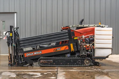 Side view of 2018 Ditch Witch JT10 HDD drill with track undercarriage, drill pipe rack, and rear fluid tank.