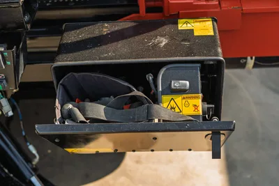 Close-up of open storage compartment on 2020 Ditch Witch JT24 HDD drill, showing warning decals and interior accessory pouch.