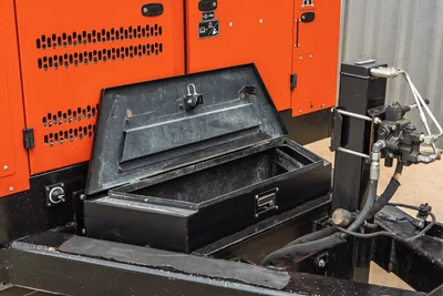 2023 Ditch Witch HX50 open lockable steel toolbox with drawer, hydraulic manifold and hoses visible, orange enclosure panels