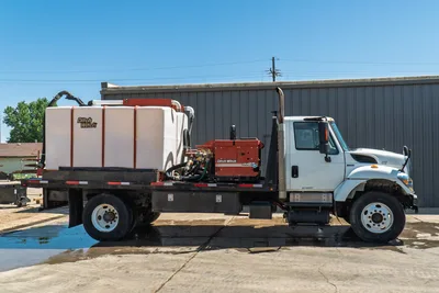 2015 International 7400 mud truck, full driver-side view, Ditch Witch FM25 mixer, white poly tank, flatbed, dual exhaust stack
