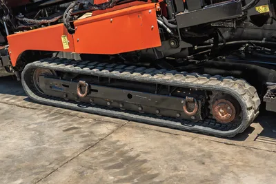 2018 Ditch Witch JT30 All Terrain rubber track close-up showing drive sprocket, tie-down D-rings, and orange undercarriage frame