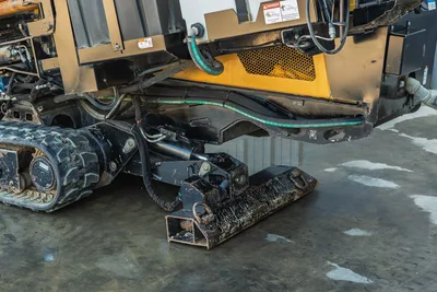 2021 Vermeer D23x30 S3 undercarriage close-up showing rubber track, hydraulic hoses, anchor plate, and yellow ventilated side panel