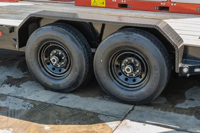 2023 MAXX-D C6X trailer tandem axle close-up showing ST235/80R16 tires, black steel wheels, and diamond-plate fenders
