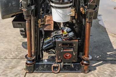 Close-up of 2018 Ditch Witch JT10 drill head, carriage, and anchor system showing hydraulic lines and worn anchor rods.