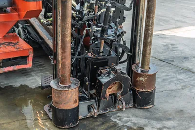 2021 Ditch Witch JT28 drill frame close-up showing carriage, hydraulic components, vise jaws, and worn drill pipe guides